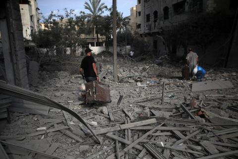 Palestinians carrying luggage walk through the massive destruction in Gaza City's Al-Rimal district, Gaza, October 10, 2023.