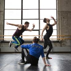 Three dancers practice in a warehouse.