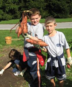 Two children hold up freshly harvested yams