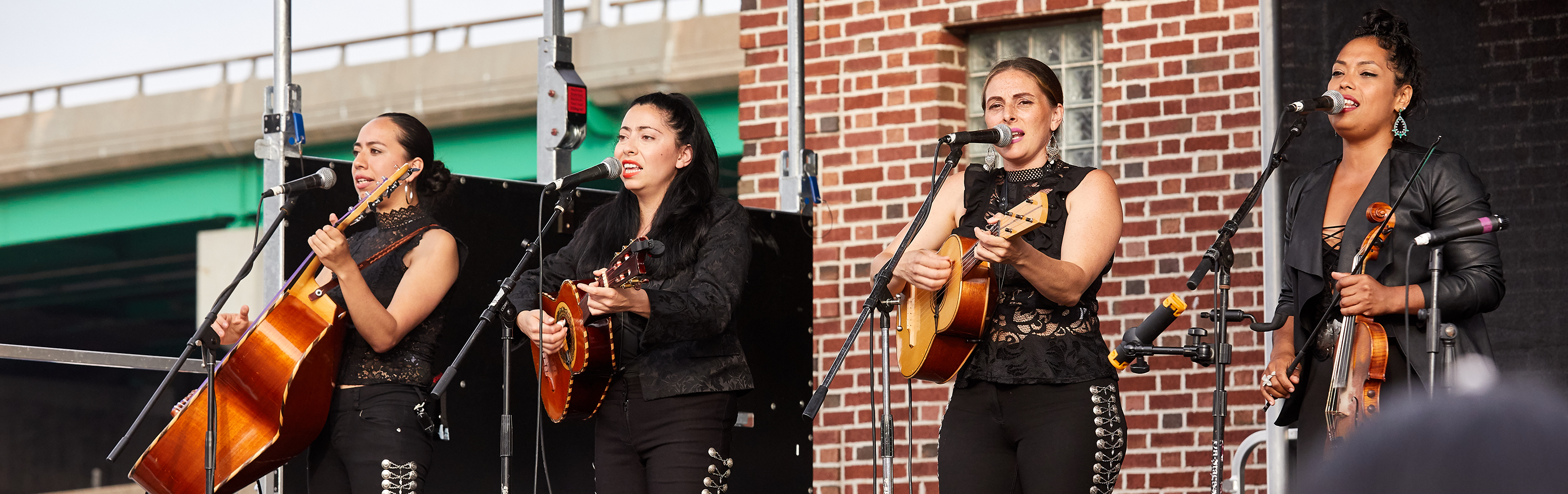 An all-female mariachi bands performs on stage for a live audience.