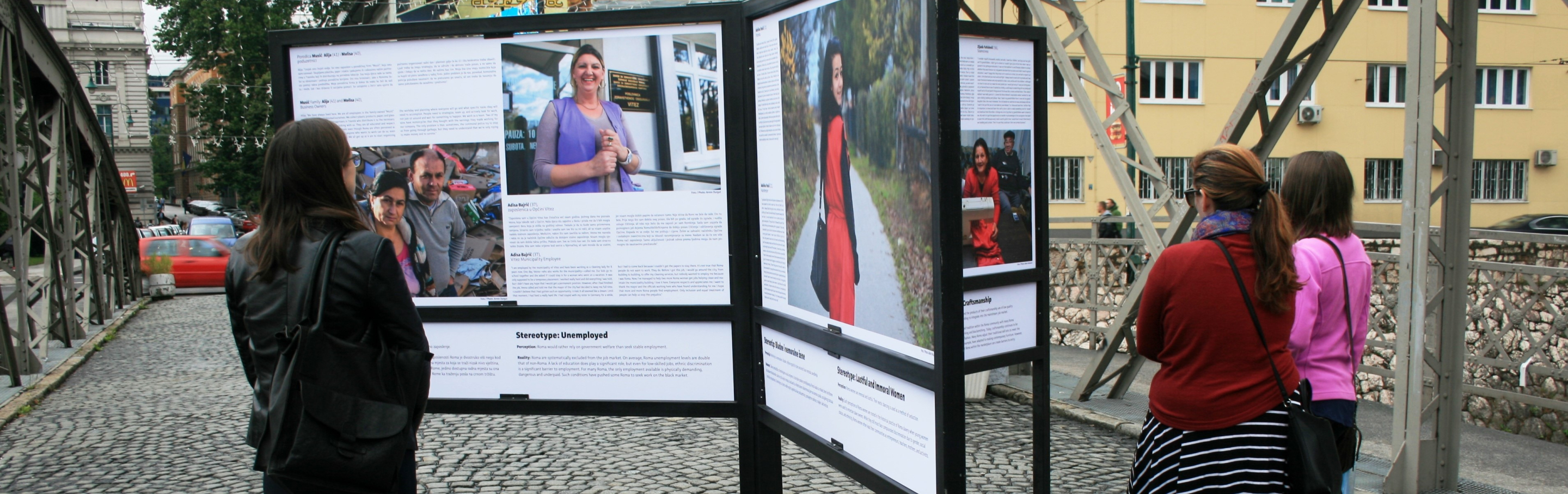 Three women review an exhibition on the Roma people in Sarajevo.