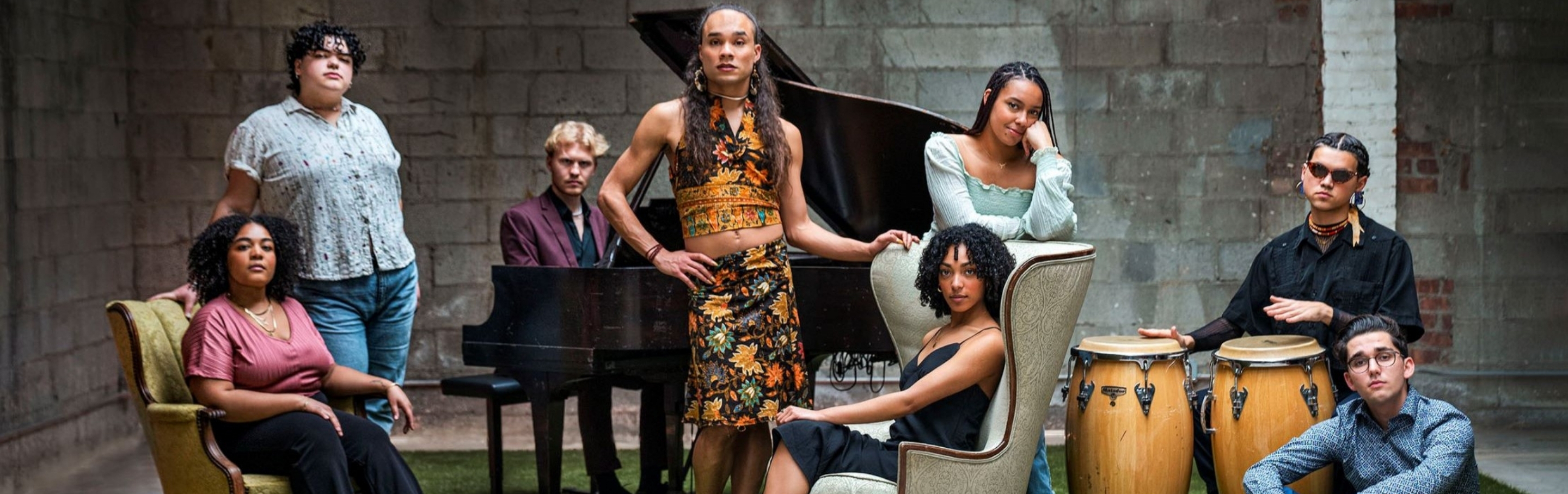 Artists pose around a piano and conga drums.