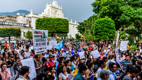 Protestors wave Guatemalan flags and slogans protesting government corruption in front of Antigua city hall. Sign reads "No more corruptionists. Guatemala isn't for sale".