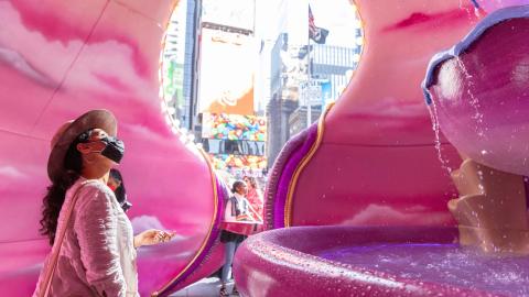 A woman admires an intricate fountain inside a pink cavernous structure in New York CIty's Times Square