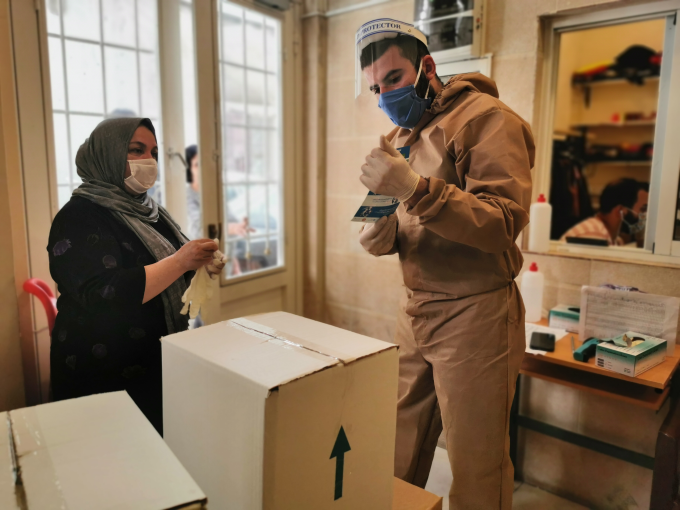 An aid worker provides food baskets and COVID information 