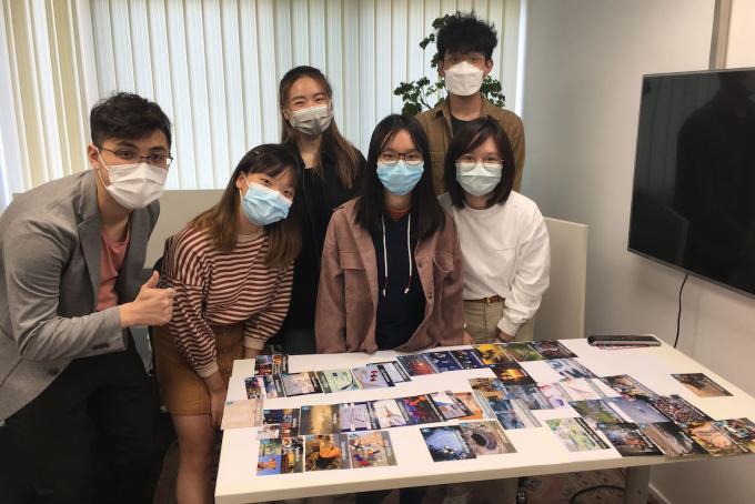 Six college students wearing medical masks pose in front of research photos