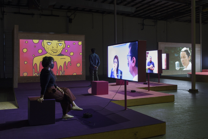 a viewer watches a film in an otherwise empty gallery