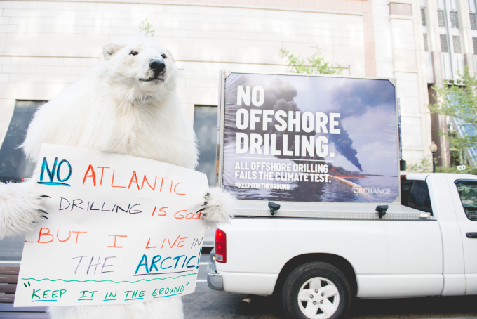 A protester in a polar bear suit holds a sign that says "No Arctic drilling."