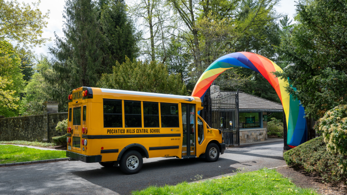 A school bus enters The Pocantico Center with a rainbow-arch at enterance