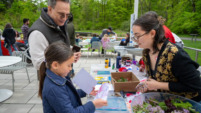 Child and parent stamp flowers into a painting