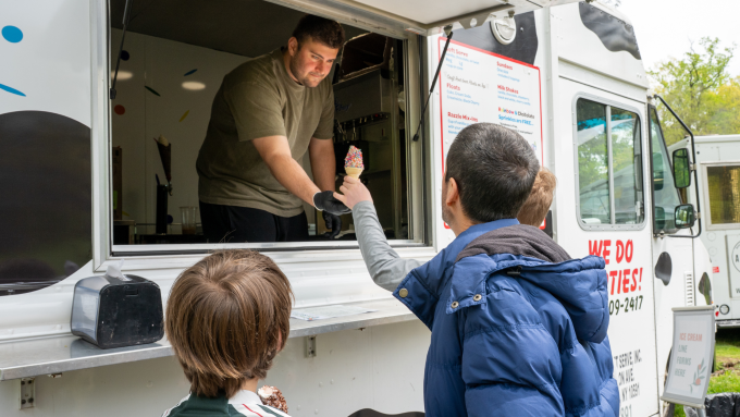 Ice cream truck serves cone to families