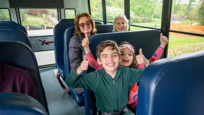 Children and elderly sit in a school bus happily