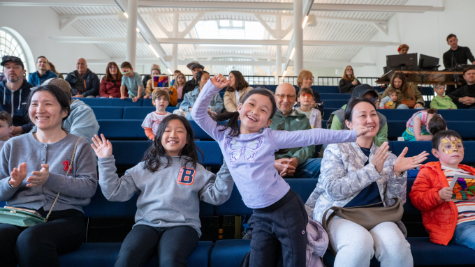 Children and family sitting happily enjoying a performance.