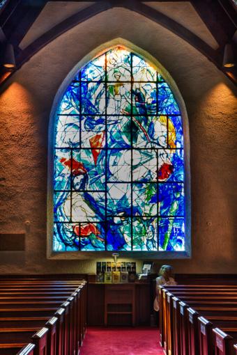 A large, primarily blue stained glass window with hints of greens and oranges, containing Christian imagery.
