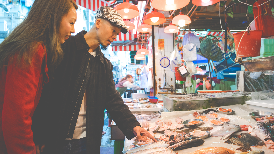 a couple shops selects their purchases at a fish market.