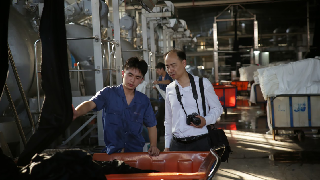 Two men inspect a machine at a factory