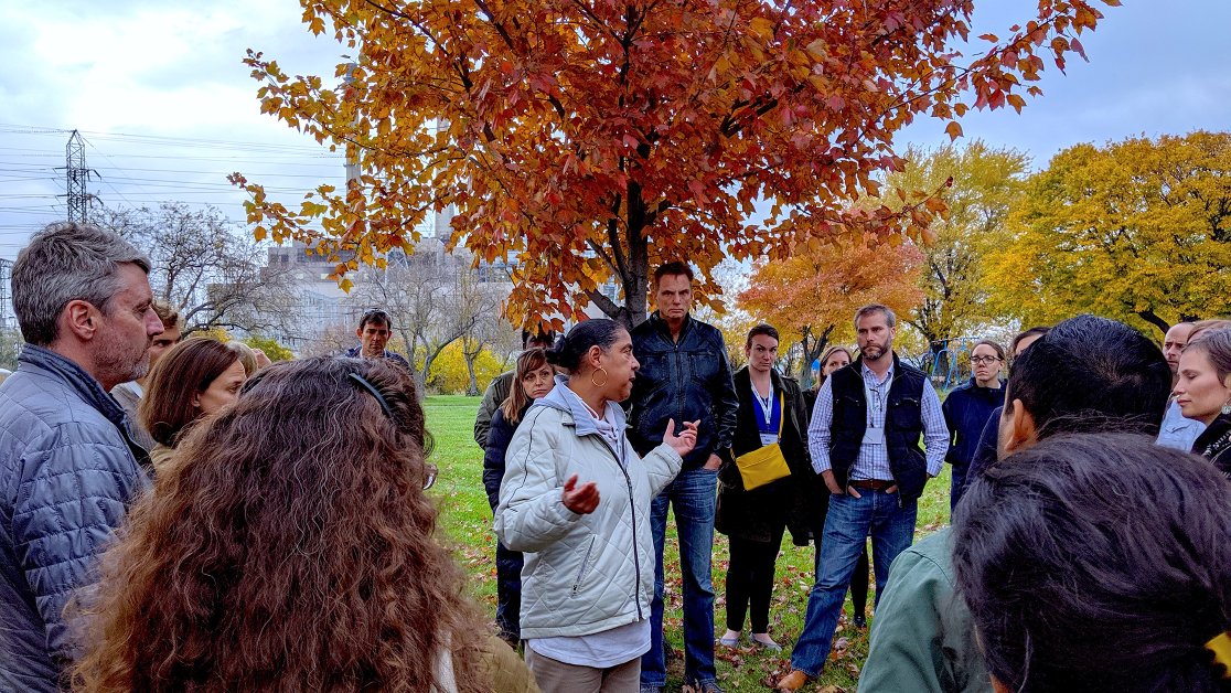 A group gathers around a maple tree in fall.