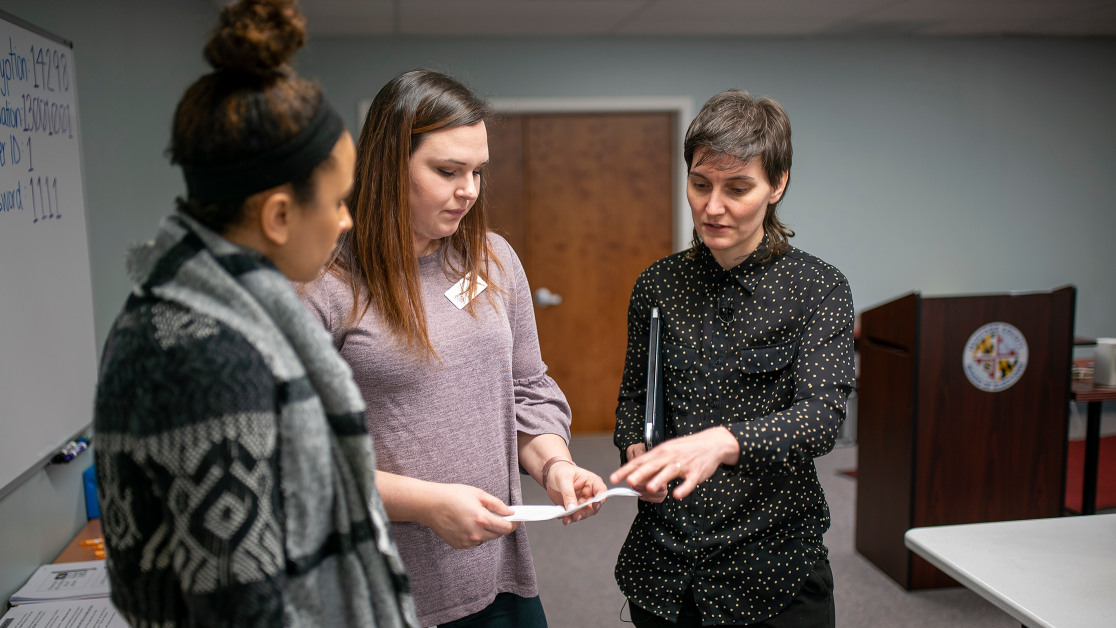Three people gather round and discuss a small piece of paper