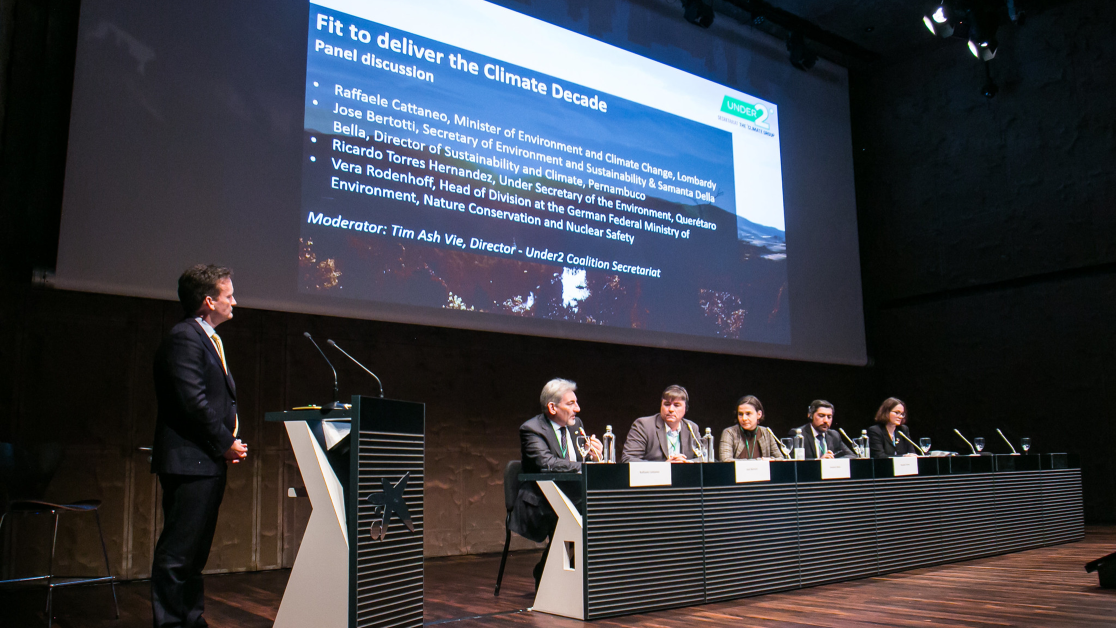 panelists on a stage in front of a slide that reads Fit to Deliver the Climate Decade