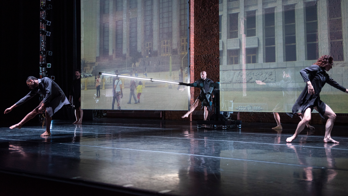Dancers on stage in front of a large screen