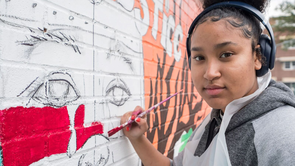 A girl paints a mural