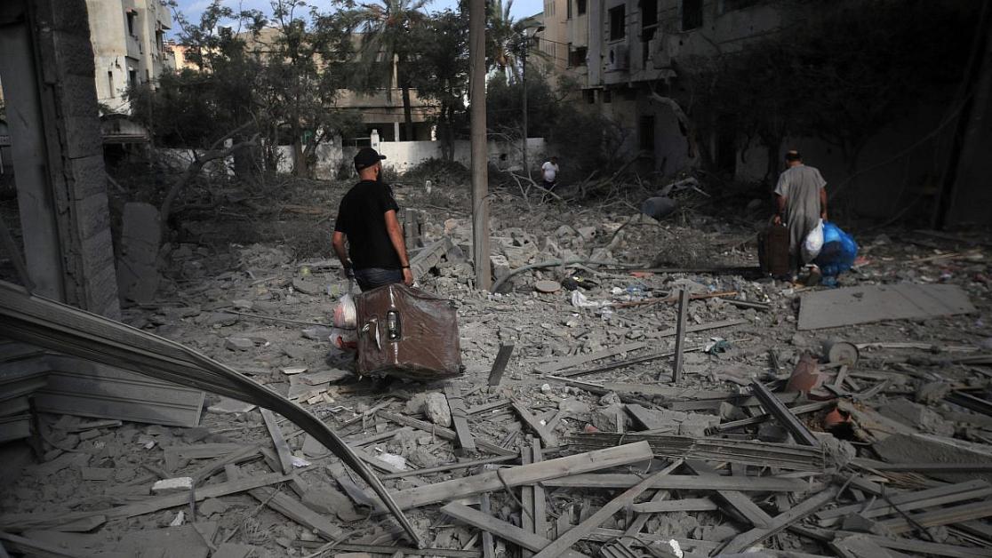 Palestinians carrying luggage walk through the massive destruction in Gaza City's Al-Rimal district, Gaza, October 10, 2023.