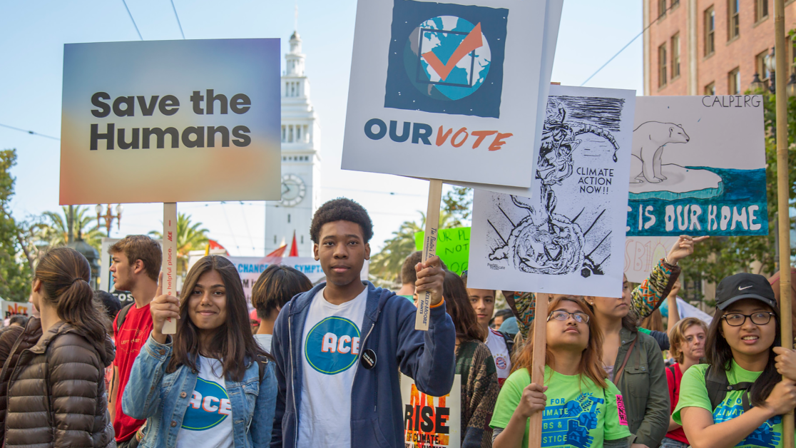 A crowd of young people holding protest signs on climate change and democracy