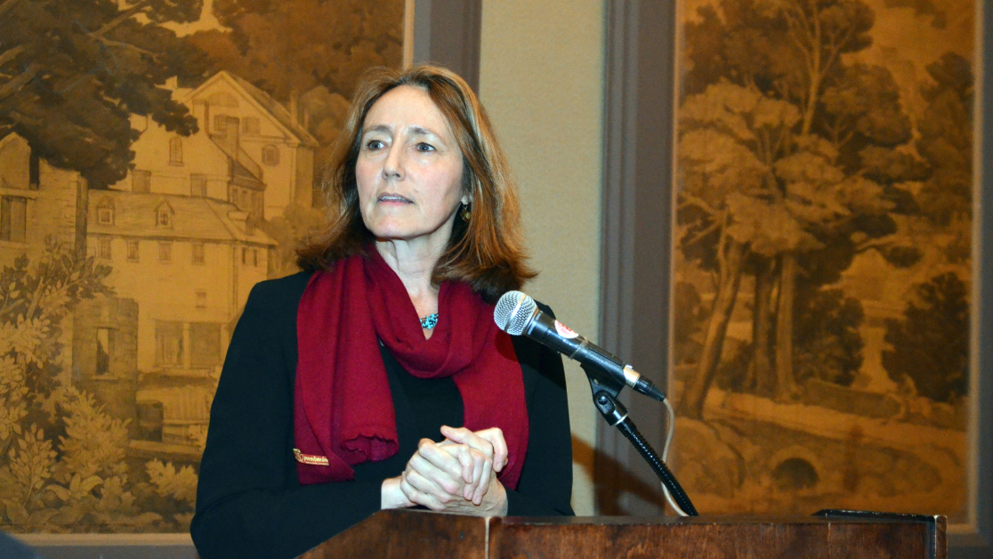Betsy Campbell addresses an audience from behind a podium. 