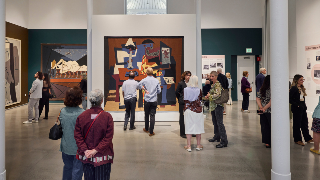 Visitors view tapestries and exhibition displays during the opening reception of Woven Wonders at the David Rockefeller Creative Arts Center.