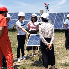 Men and women examine a solar energy array.