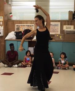A flamenco dancer demonstrates for several young children.