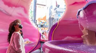 A woman admires an intricate fountain inside a pink cavernous structure in New York CIty's Times Square