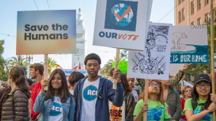 A crowd of young people holding protest signs on climate change and democracy