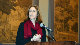 Betsy Campbell addresses an audience from behind a podium. 