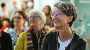 a woman with short grey hair smiles at something out of frame