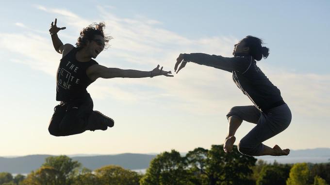 Two leaping dancers are suspended in-air with the Hudson River skyline at Pocantico behind them