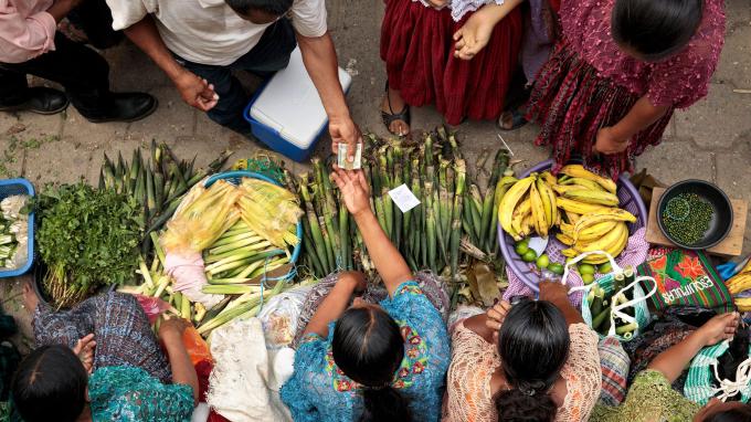 A birds-eye view of women exchanging money and fresh produce