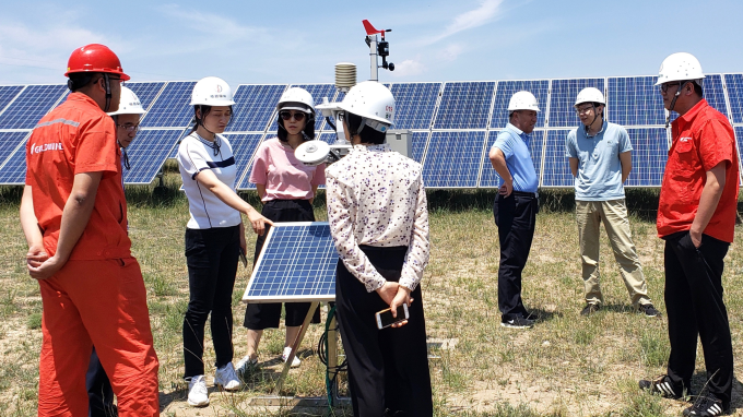 Men and women examine a solar energy array.
