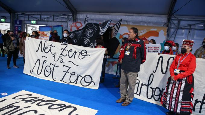 Representatives of civil society protesting at COP26 in Glasgow hold a sign that reads "Net Zero is Not Zero."