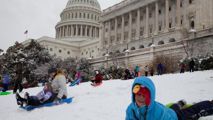 Children and families sled on the snow-covered lawn of the US Capitol building in 2014.
