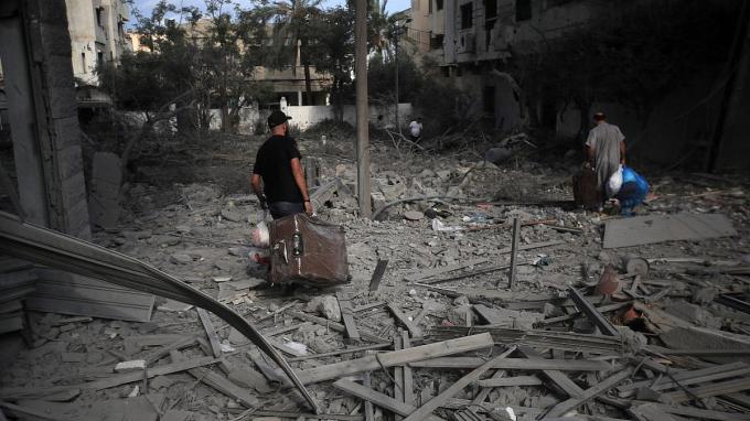 Palestinians carrying luggage walk through the massive destruction in Gaza City's Al-Rimal district, Gaza, October 10, 2023.