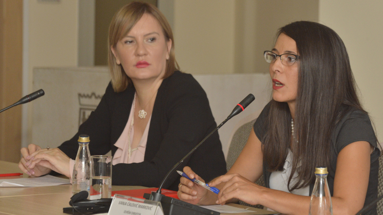 Two women speak into microphone at a conference