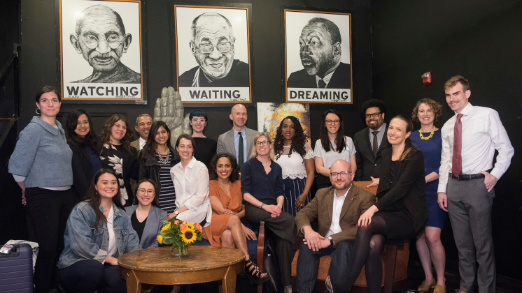 A large group of people poses in front of images of Gandhi, the Dalai Lama, and Martin Luther King, Jr.
