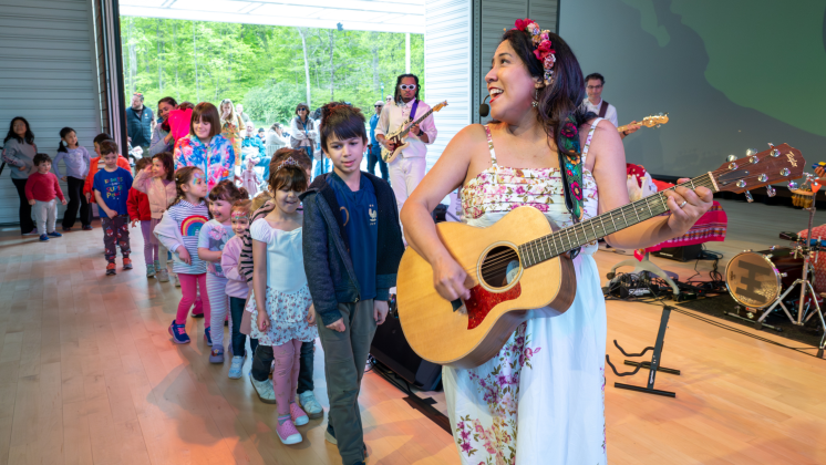 Grammy nominated singer-songwriter Flor Bromley plays the guitar with children following on line