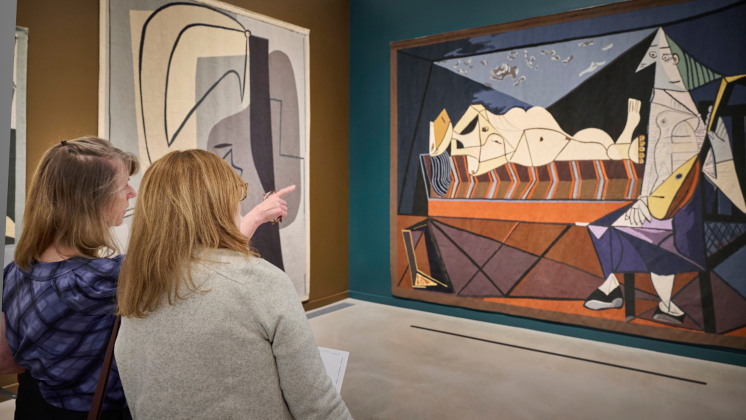 Two visitors view large handwoven tapestries based on Pablo Picasso’s artworks in the Woven Wonders: Kykuit’s Picasso Tapestries exhibition at the David Rockefeller Creative Arts Center.